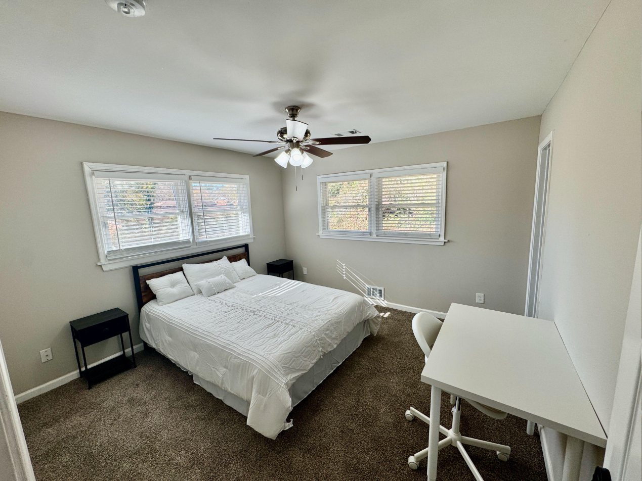 Room 2: corner bedroom with four windows, queen bed and desk